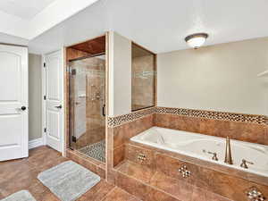 Full bath with a textured ceiling, a tub with jets, a stall shower, and tile patterned floors