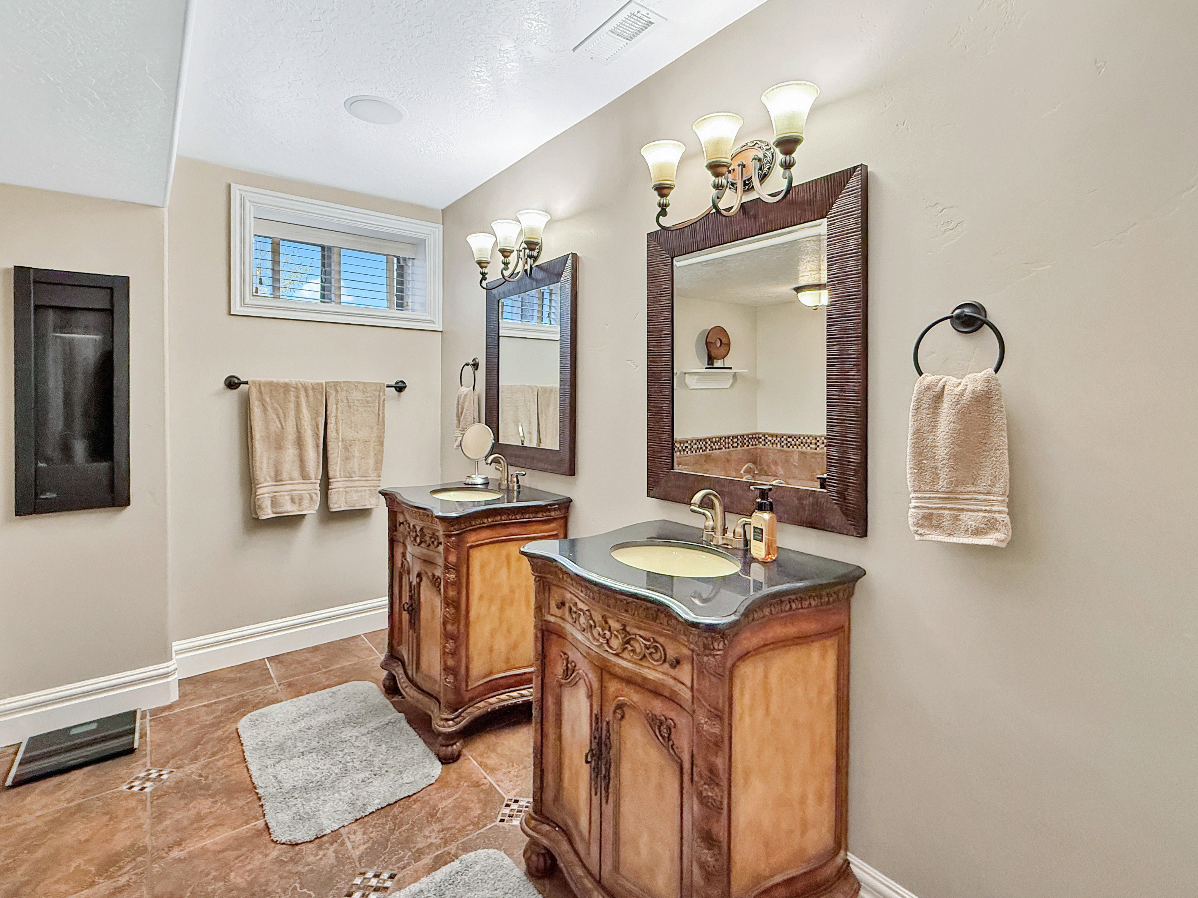 Bathroom featuring two vanities, a textured ceiling, and light tile patterned floors