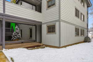 Snow covered property entrance featuring heating fuel and a wooden deck
