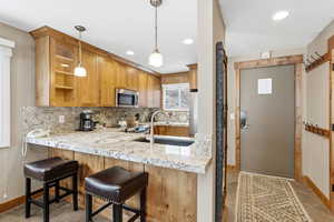 Kitchen featuring decorative light fixtures, tasteful backsplash, stainless steel appliances, light stone countertops, and recessed lighting