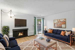 Living area with a lit fireplace and wood finished floors