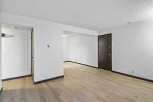 Unfurnished room with a textured ceiling and light wood-type flooring