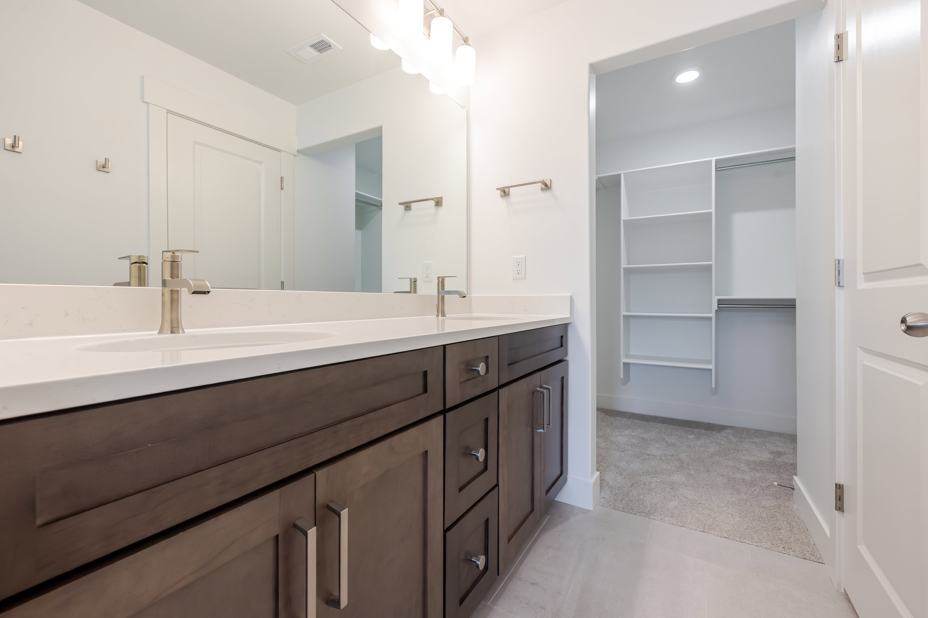 Bathroom featuring a dual vanity with white countertops, undermount sinks, brushed nickel faucets, and a large mirror