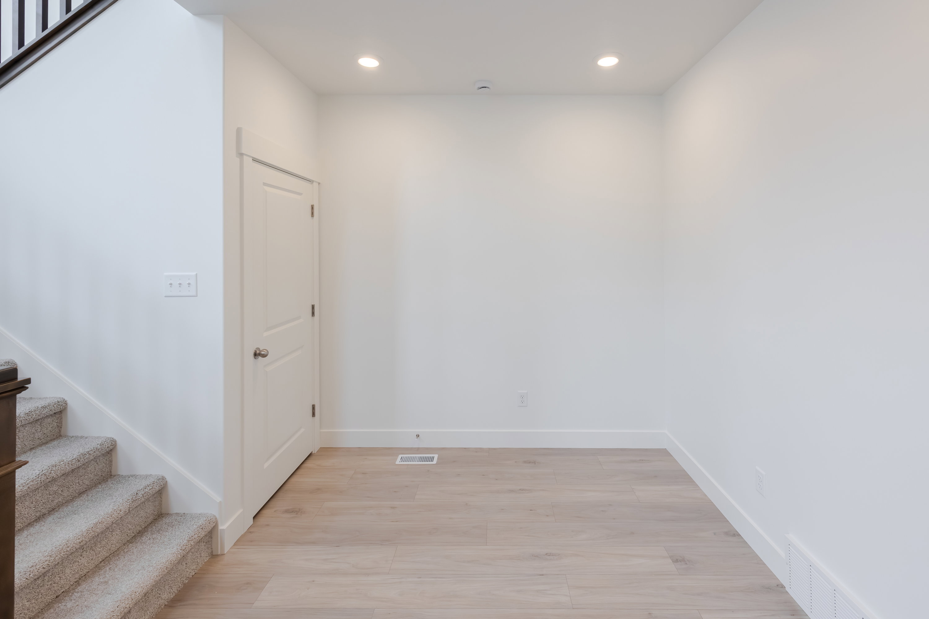Open concept area featuring light wood-finish flooring, recessed lighting, and crisp white baseboards