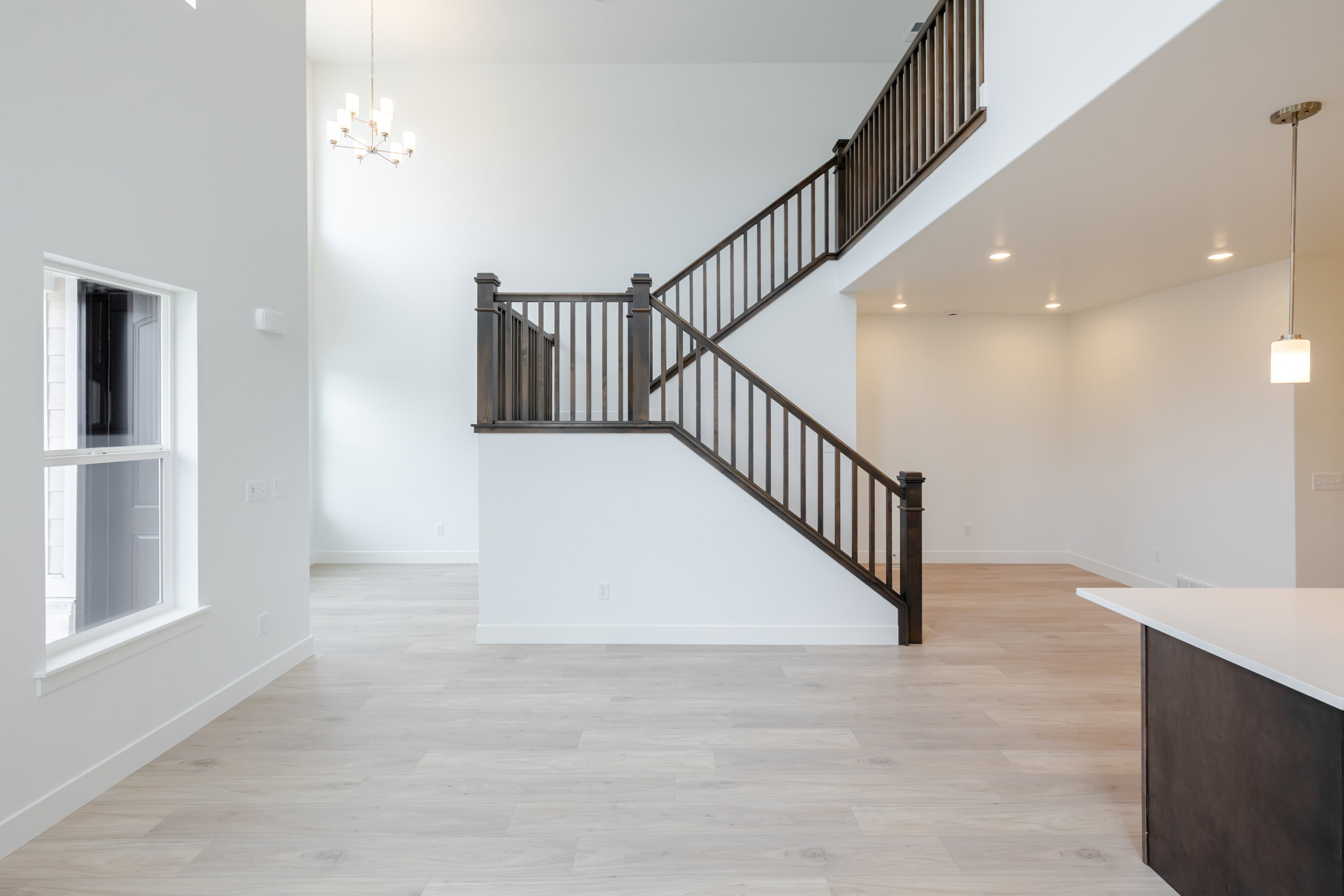 Two-story entryway featuring a contemporary chandelier and dark wood-finish staircase with matching railings