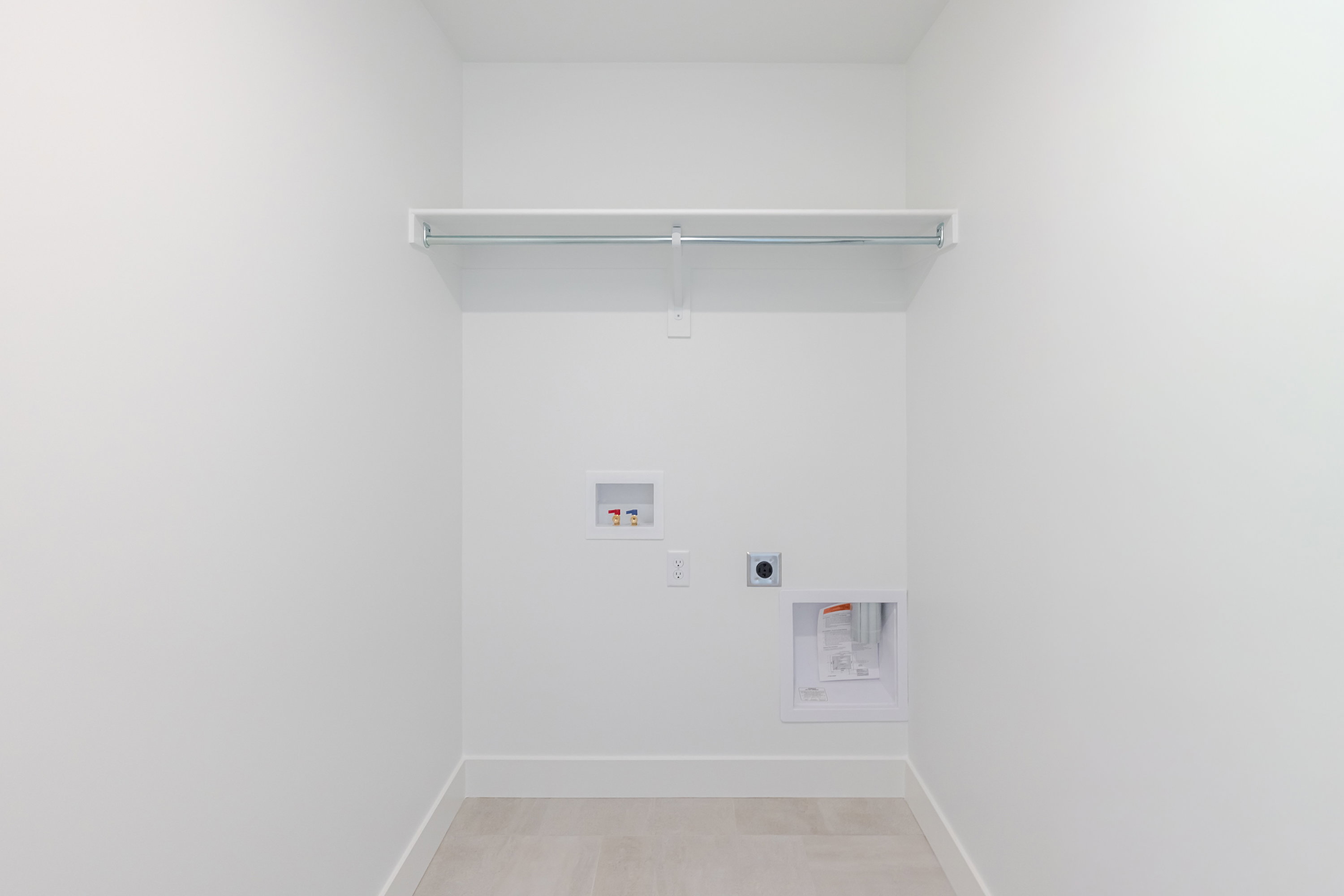 Utility area with white walls, a built-in shelf, and a hanging rod