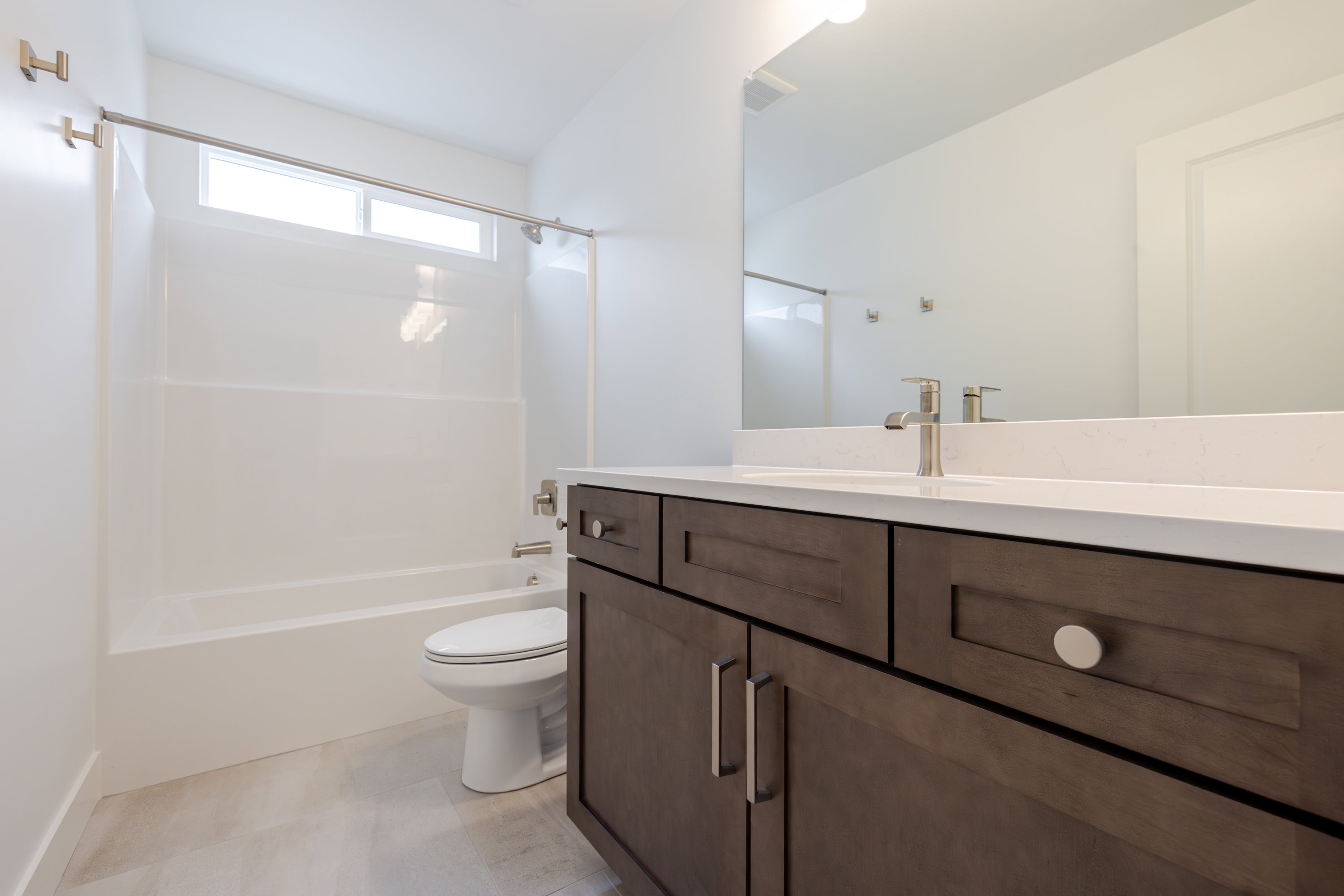 Bathroom featuring a spacious vanity with wood-finish cabinetry, a white countertop, and brushed nickel hardware