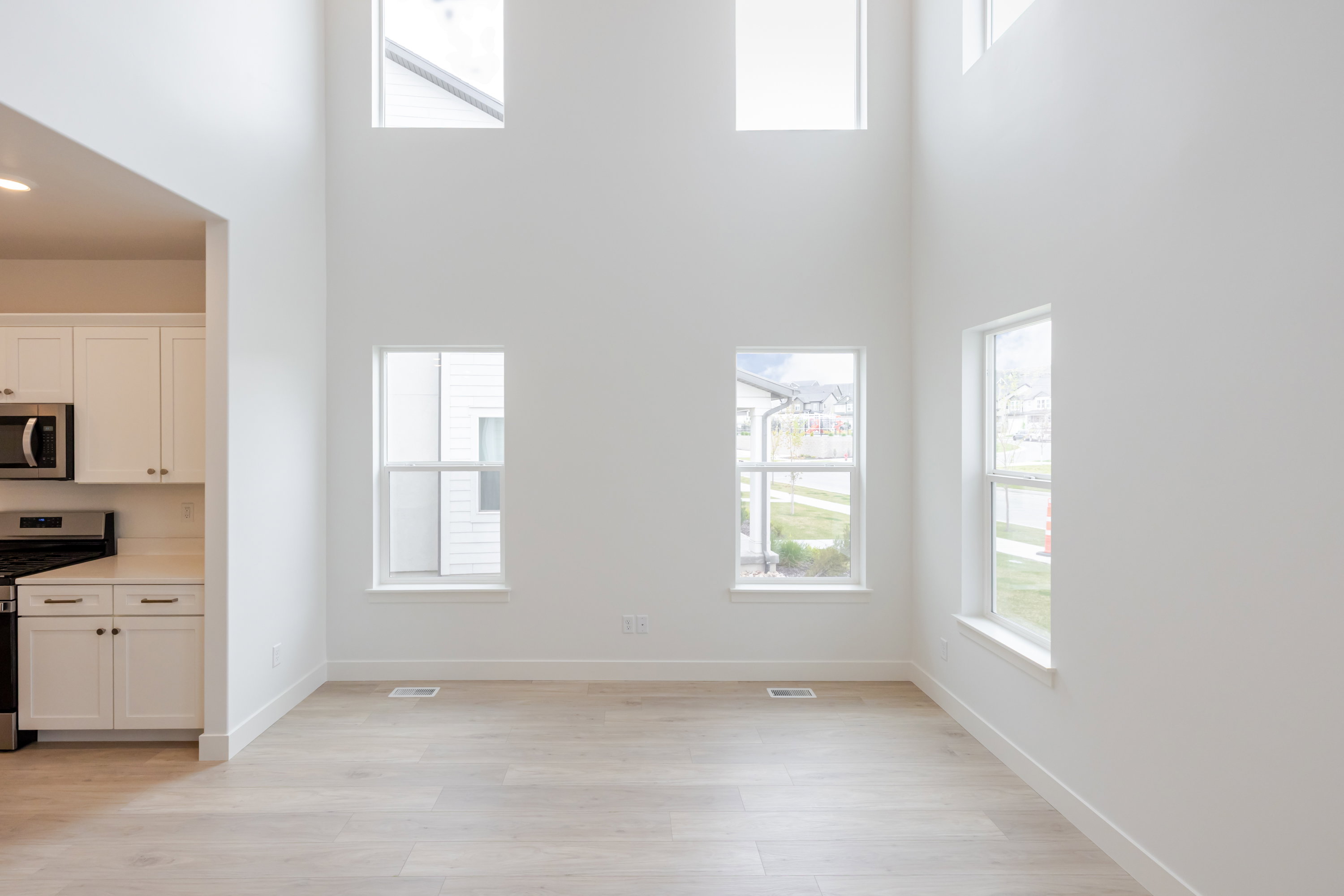 Expansive living space featuring high ceilings, light wood-finish flooring, and multiple windows