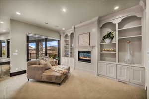 Living area featuring built in shelves, recessed lighting, a glass covered fireplace, carpet flooring, and a mountain view