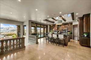 Kitchen with glass insert cabinets, a kitchen breakfast bar, an island with sink, recessed lighting, and a mountain view