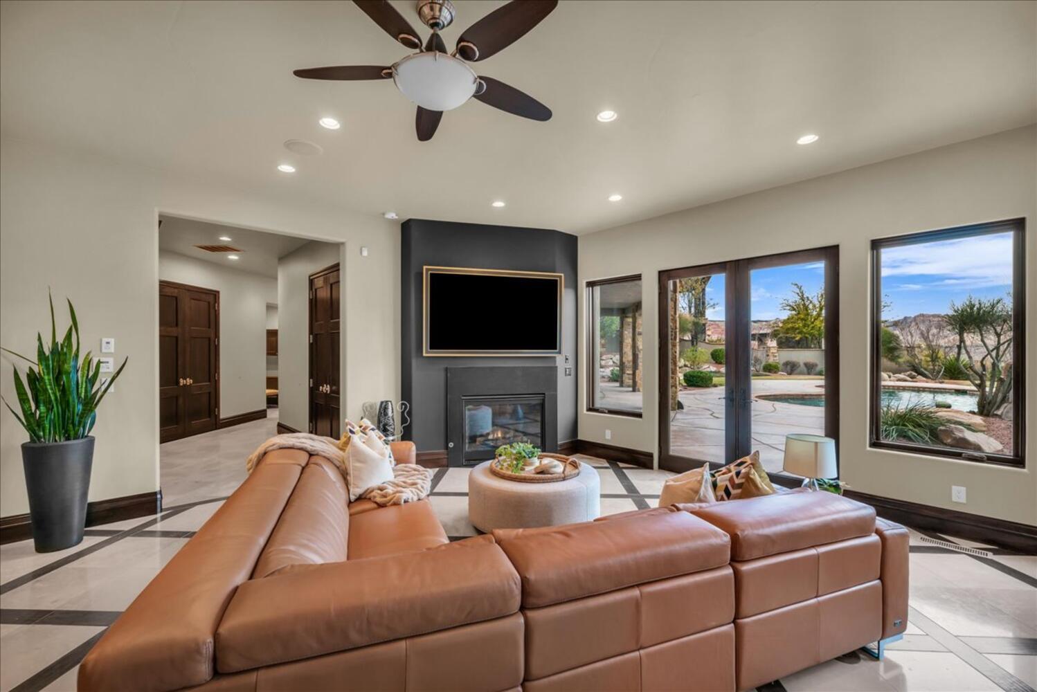 Living room featuring inlaid floor details, recessed lighting, a large fireplace, and a ceiling fan