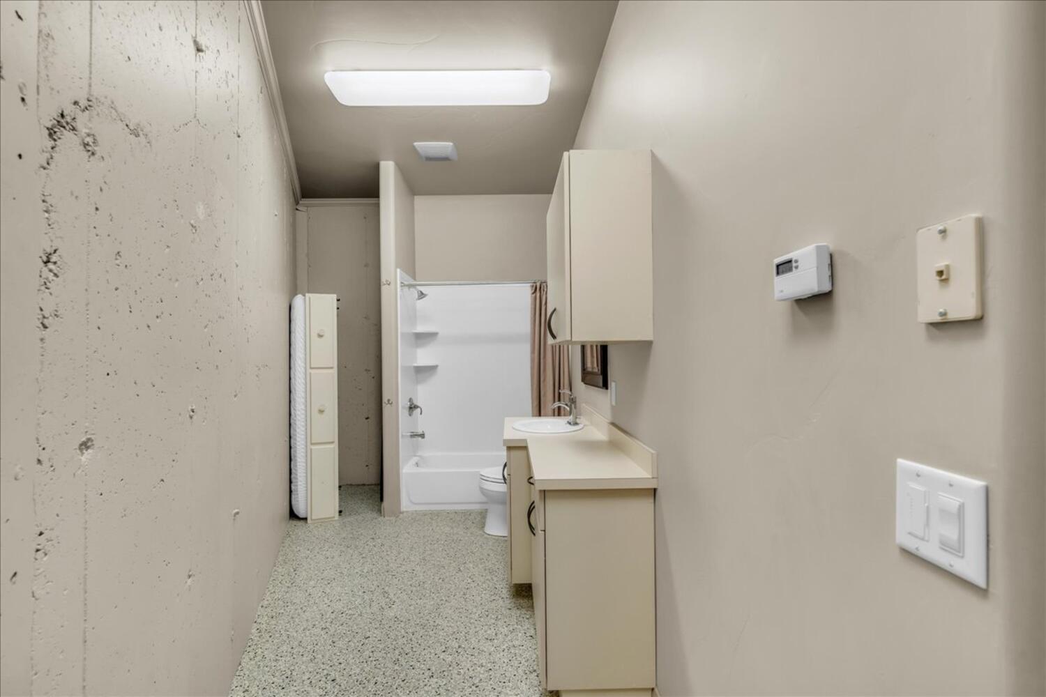 Corridor with dark aggregate flooring and a sink