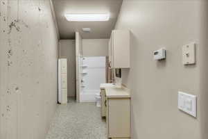 Corridor with dark aggregate flooring and a sink