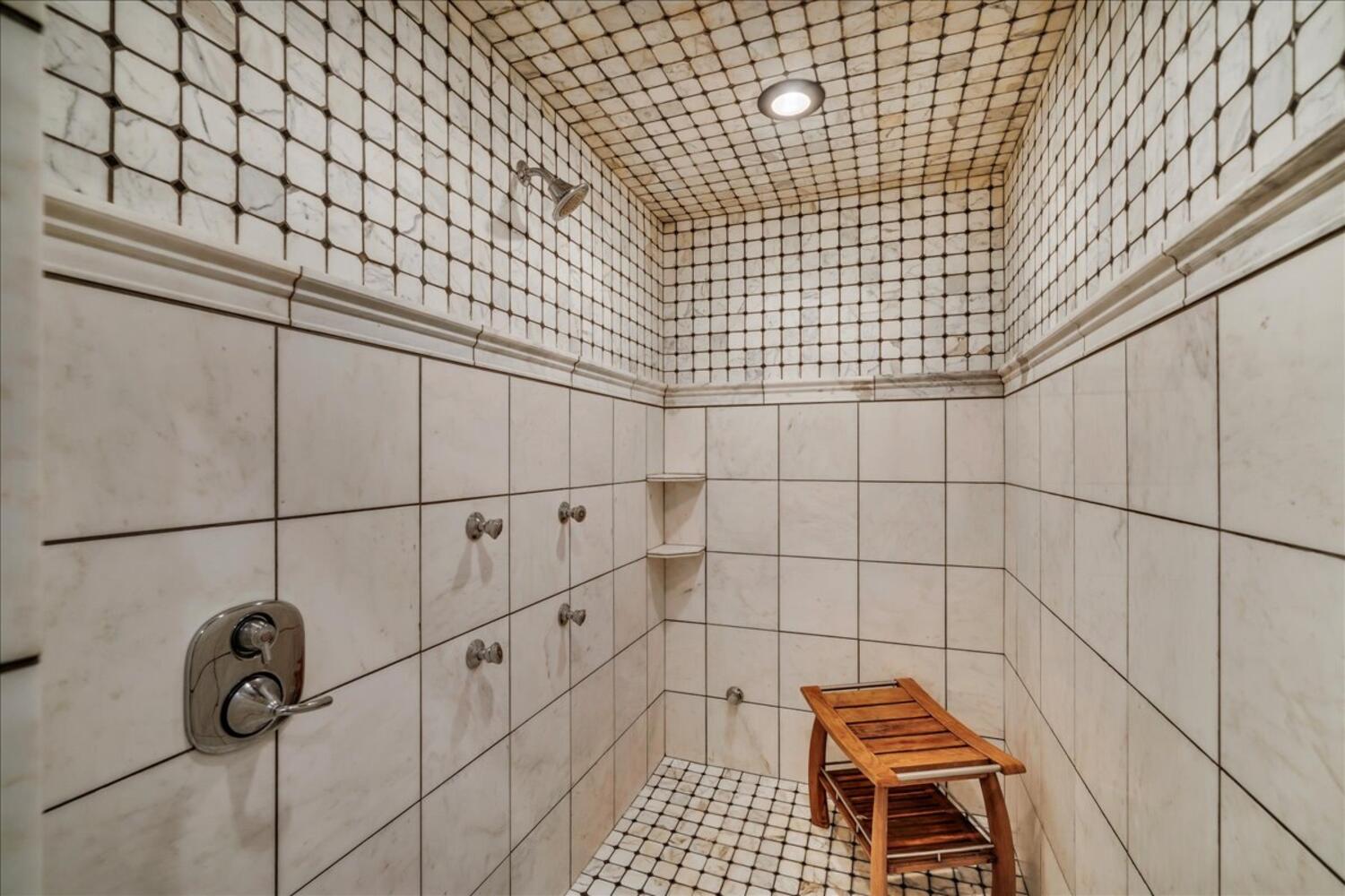 Bathroom view of a tile shower and recessed lighting