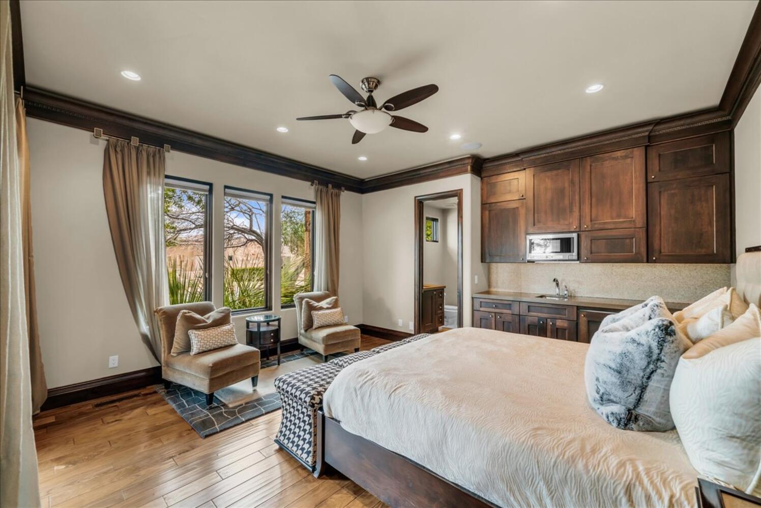 Bedroom with ornamental molding, light wood-style flooring, a ceiling fan, connected bathroom, and recessed lighting