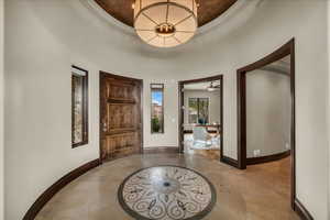 Foyer with inlaid floor details, a tray ceiling, and light tile patterned flooring