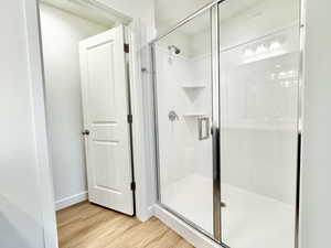 Bathroom with light wood-type flooring and a shower stall
