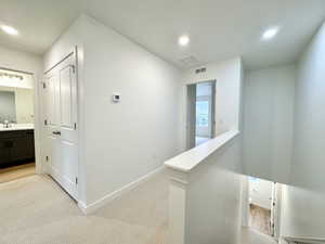 Corridor featuring an upstairs landing, light carpet, and recessed lighting