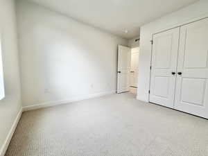 Unfurnished bedroom featuring carpet and a closet