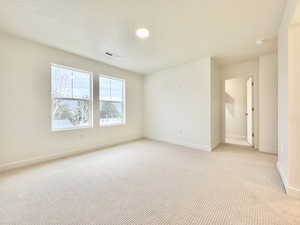 Spare room with light carpet and a textured ceiling