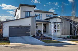 View of front facade featuring a porch, concrete driveway, a garage, and roof with shingles