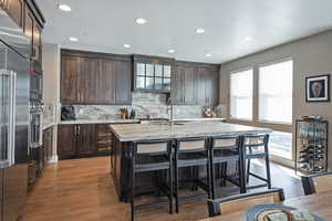 Kitchen featuring dark brown cabinetry, built in appliances, a breakfast bar, and recessed lighting