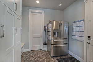 Kitchen featuring stainless steel fridge, recessed lighting, and white cabinetry