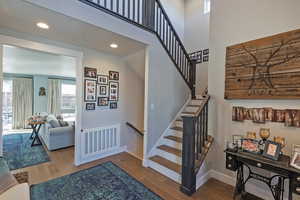 Stairs featuring wood finished floors, recessed lighting, and a towering ceiling