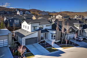 View of front of property featuring a residential view, driveway, an attached garage, and roof with shingles