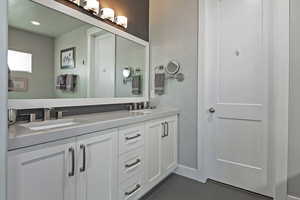 Full bathroom featuring double vanity and dark tile patterned floors