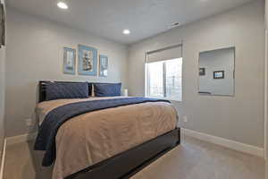 Bedroom with light colored carpet and recessed lighting