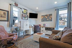 Living room with wood finished floors, recessed lighting, and a desk