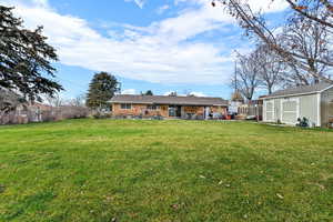 Back of property with a storage unit, brick siding, a patio, and a chimney