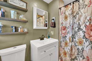 Full bath with a textured wall, vanity, and a shower with curtain