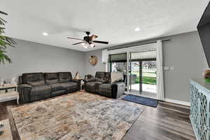 Living area featuring recessed lighting, dark wood-type flooring, a ceiling fan, and a textured ceiling