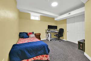 Carpeted bedroom featuring a closet and an office area