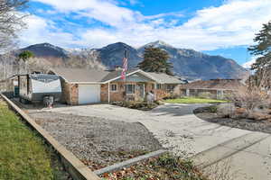 Ranch-style house featuring concrete driveway, a chimney, a mountain view, a garage, and brick siding
