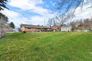 Back of house with a shed, brick siding, and a patio