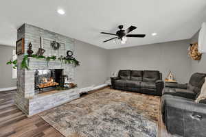 Living area with wood finished floors, a textured ceiling, a brick fireplace, recessed lighting, and ceiling fan