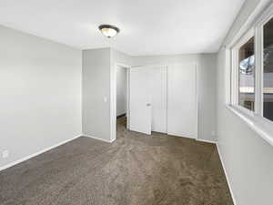 Unfurnished bedroom with dark carpet and a closet