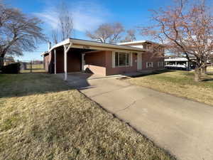View of front of property featuring an attached carport, concrete driveway, and brick siding