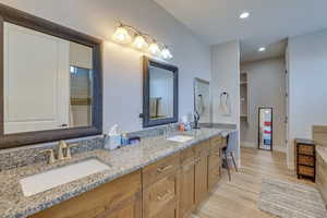 Bathroom with double vanity, recessed lighting, a walk in closet, and light wood finished floors