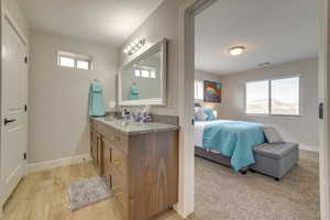 Ensuite bathroom featuring plenty of natural light, vanity, and light wood-type flooring