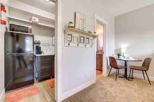 Kitchen with freestanding refrigerator, light countertops, and light colored carpet