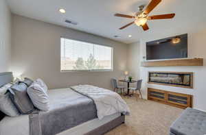Bedroom featuring carpet floors, recessed lighting, a ceiling fan, and a glass covered fireplace