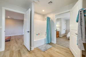 Full bath with shower / tub combo with curtain, ensuite bathroom, light wood-style floors, and recessed lighting
