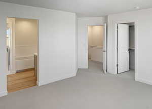 Unfurnished bedroom with light colored carpet and a walk in closet