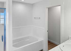 Full bath with vanity, a bath, and wood finished floors