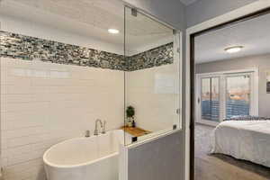 Ensuite bathroom featuring a freestanding tub, carpet floors, and tile walls