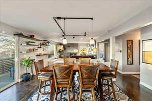 Dining space with track lighting, dark wood-style floors, and a fireplace
